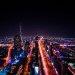 A breathtaking aerial view of Dubai's cityscape at night, highlighting the illuminated Burj Khalifa and surrounding skyscrapers.